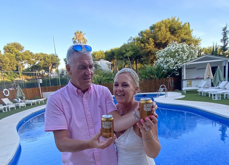 Couple holding cans poolside